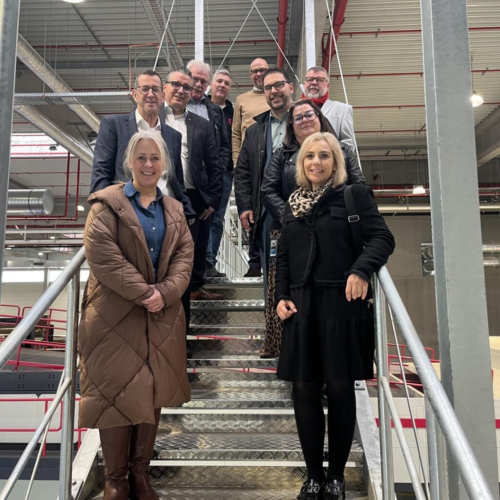 Mitglieder der Aufsichtsrats- und Gesellschafterversammlung posieren auf einer Treppe im Wellpappformatwerk PW15 für ein Gruppenfoto.