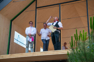 Drei Männer stehen im Rohbau der Bergvillen, u. a. der Bauherr Alois Ruppert